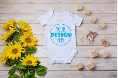 White baby short sleeve bodysuit mockup with yellow sunflowers, wooden