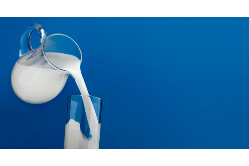 pouring-milk-in-glass-isolated-on-blue-background