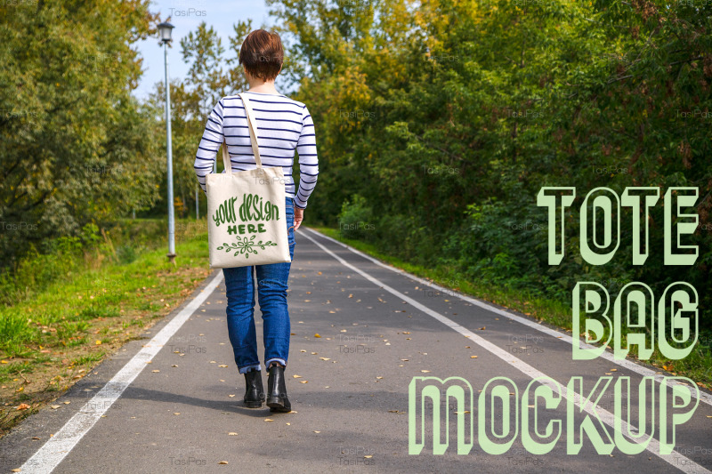 woman-holding-tote-bag-walking-in-the-park-mockup