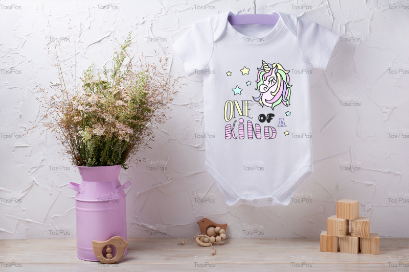 white-baby-short-sleeve-bodysuit-mockup-with-wild-flowers-and-wooden-c