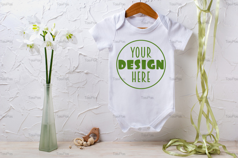white-baby-short-sleeve-bodysuit-mockup-with-lily-and-green-ribbon