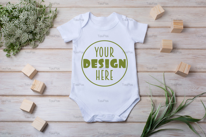 white-baby-short-sleeve-bodysuit-mockup-with-green-grass-and-white-flo