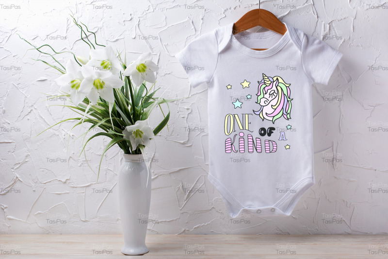 white-baby-short-sleeve-bodysuit-mockup-with-lily-bouquet