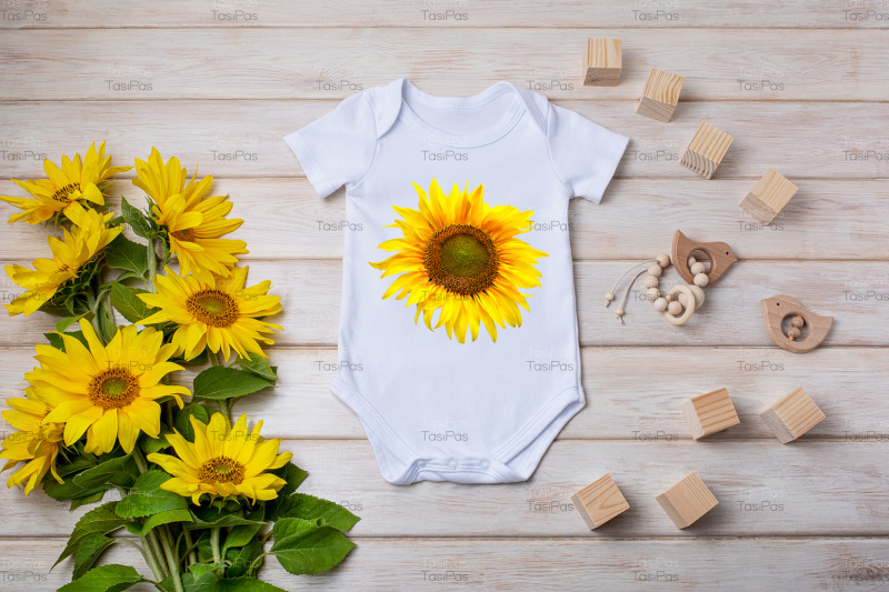 white-baby-short-sleeve-bodysuit-mockup-with-yellow-sunflowers-wooden