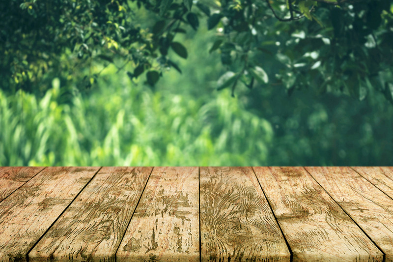 empty-wooden-deck-table-old-rustic-plank-with-foliage-bokeh-background